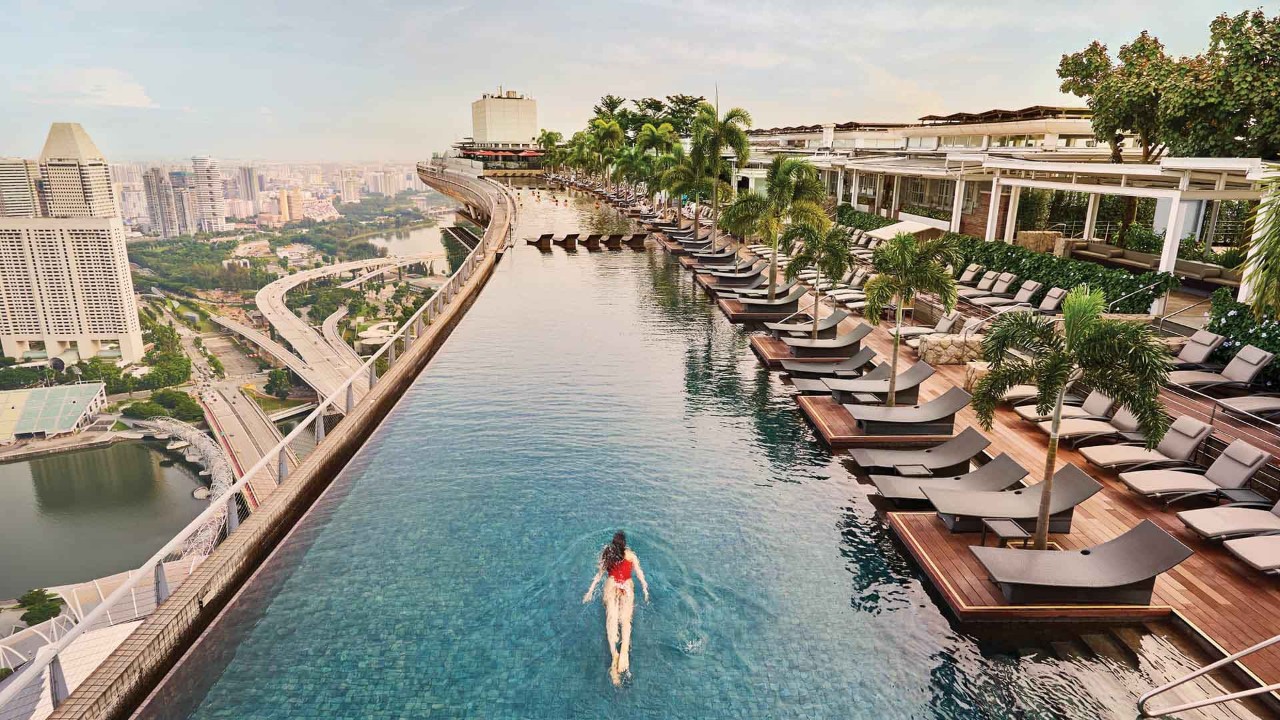 The iconic Infinity Pool at Marina Bay Sands, Singapore with rows of sun lounger in black	