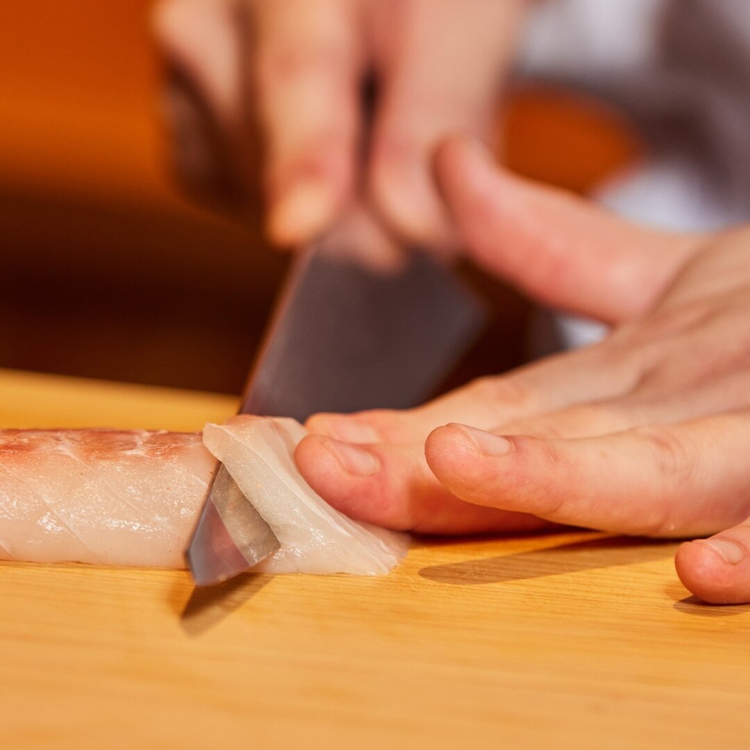 Chef preparing a slice of sashimi at an omakase restaurant in Singapore