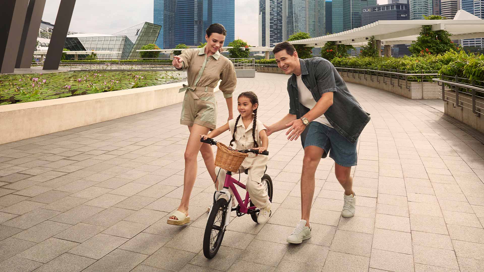 Family of three with a kid riding a bicycle for an engaging Mother's Day activity
