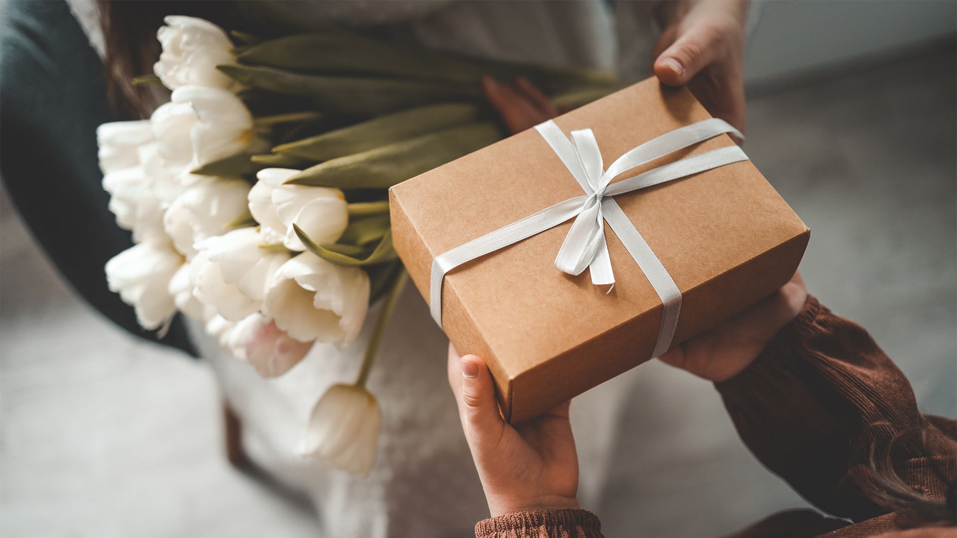 Child handing present and white tulips to mom to celebrate Mother's Day in Singapore