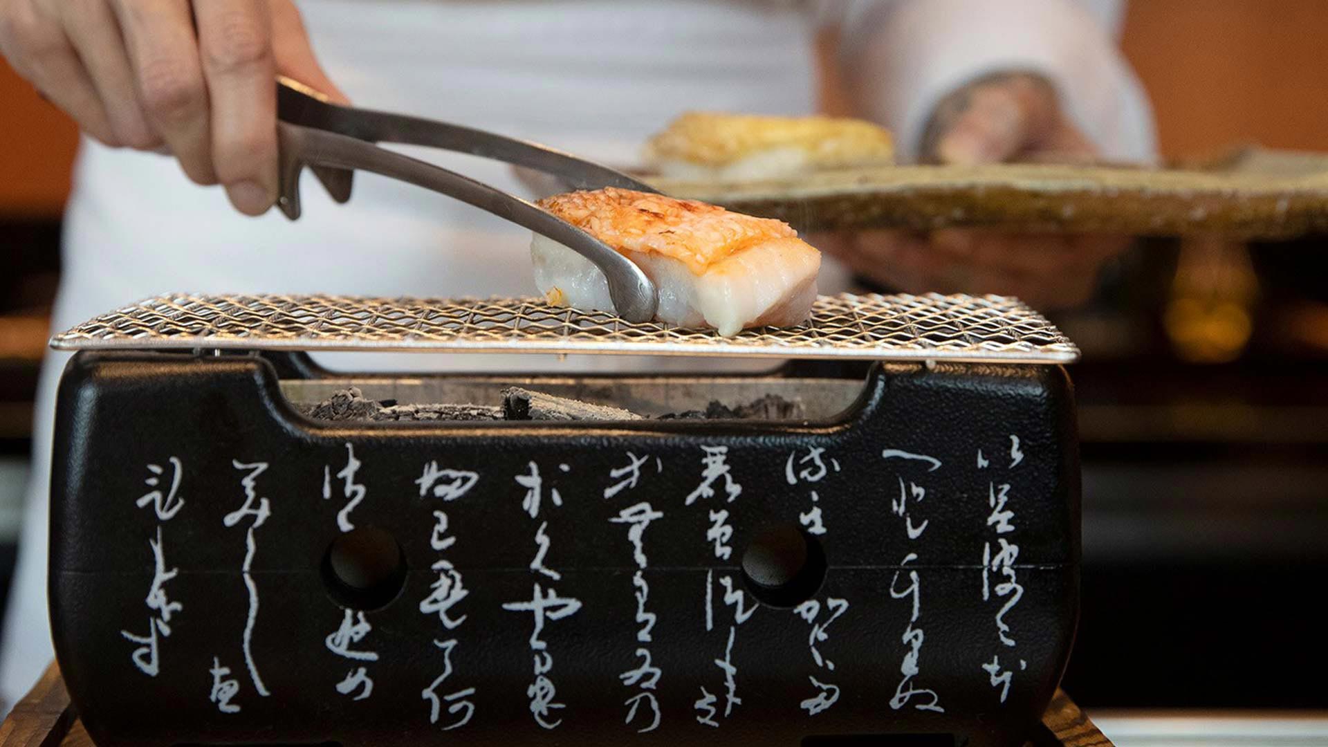 Chef gilling fish over charcoal at Waku Ghin, a restaurant to hold private dining events