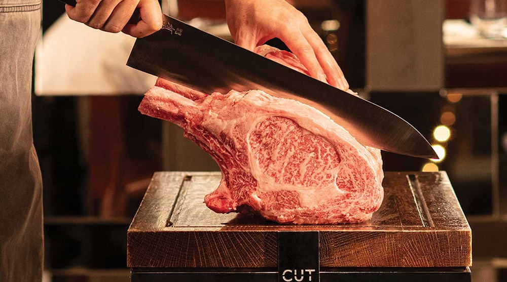 Chef cutting a bone in wagyu, preparing a Father's Day dinner at CUT, Singapore