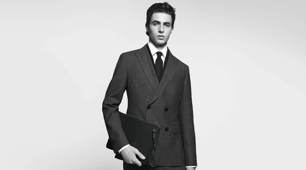 Men dressed in a smart suit with a leather pouch from BOSS, which carries items perfect for a Valentine's Day gift