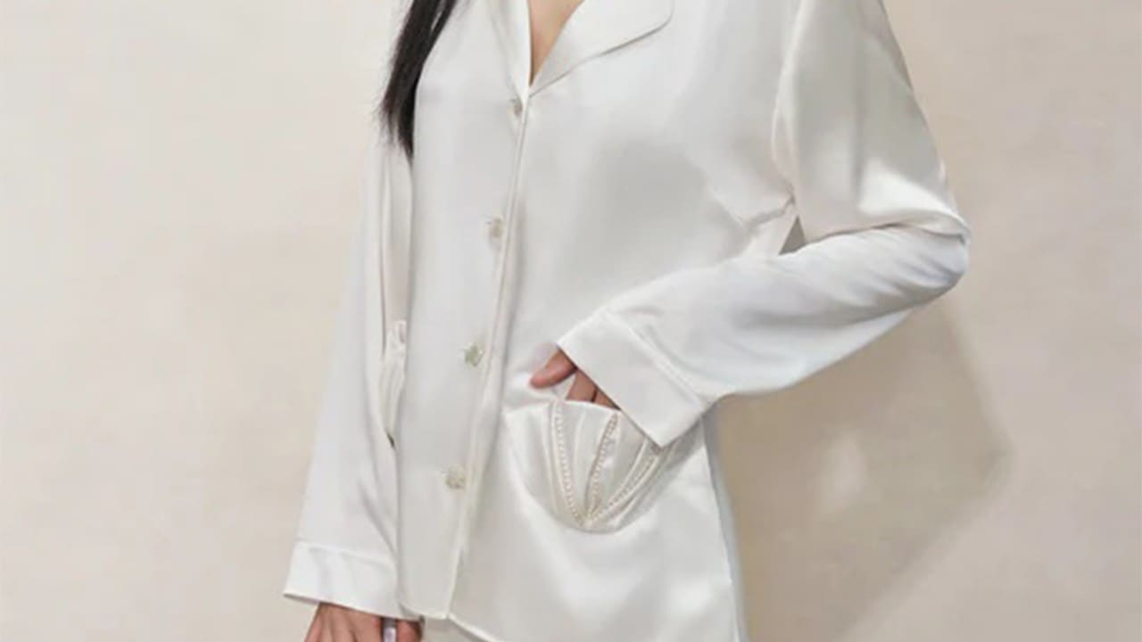 Woman wearing a silk pyjama with a shell-looking pocket in white for housewarming gift