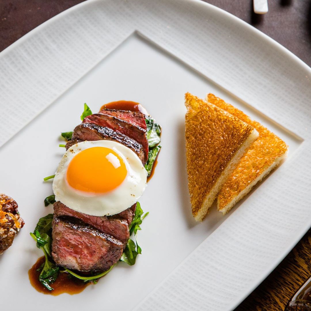 Steak topped with sunny side up and toast on the side for a 2024 Mother's Day brunch at CUT
